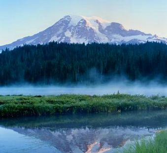 Image of a misty lake with snow capped mountains in the distance